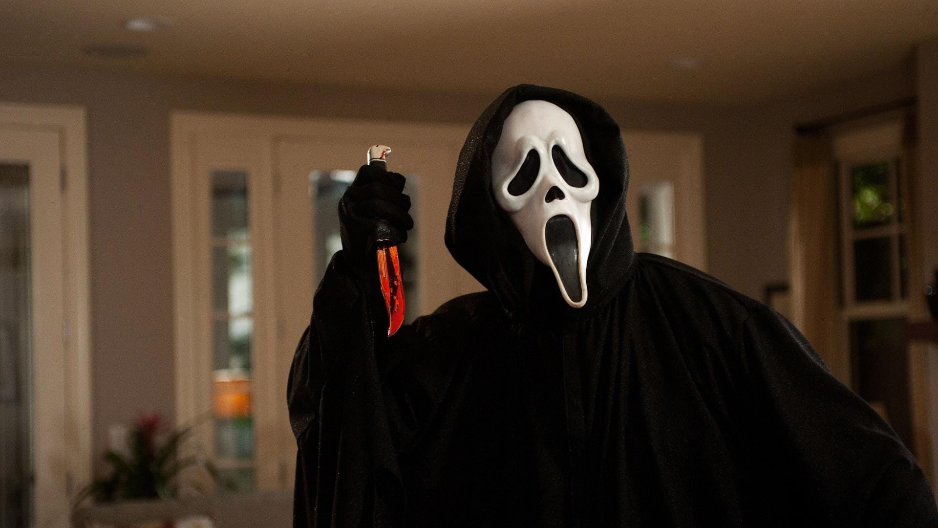 El asesino enmascarado de Ghostface, ataviado con una sotana negra y una máscara blanca con un siniestro grito, alza un cuchillo sangriento